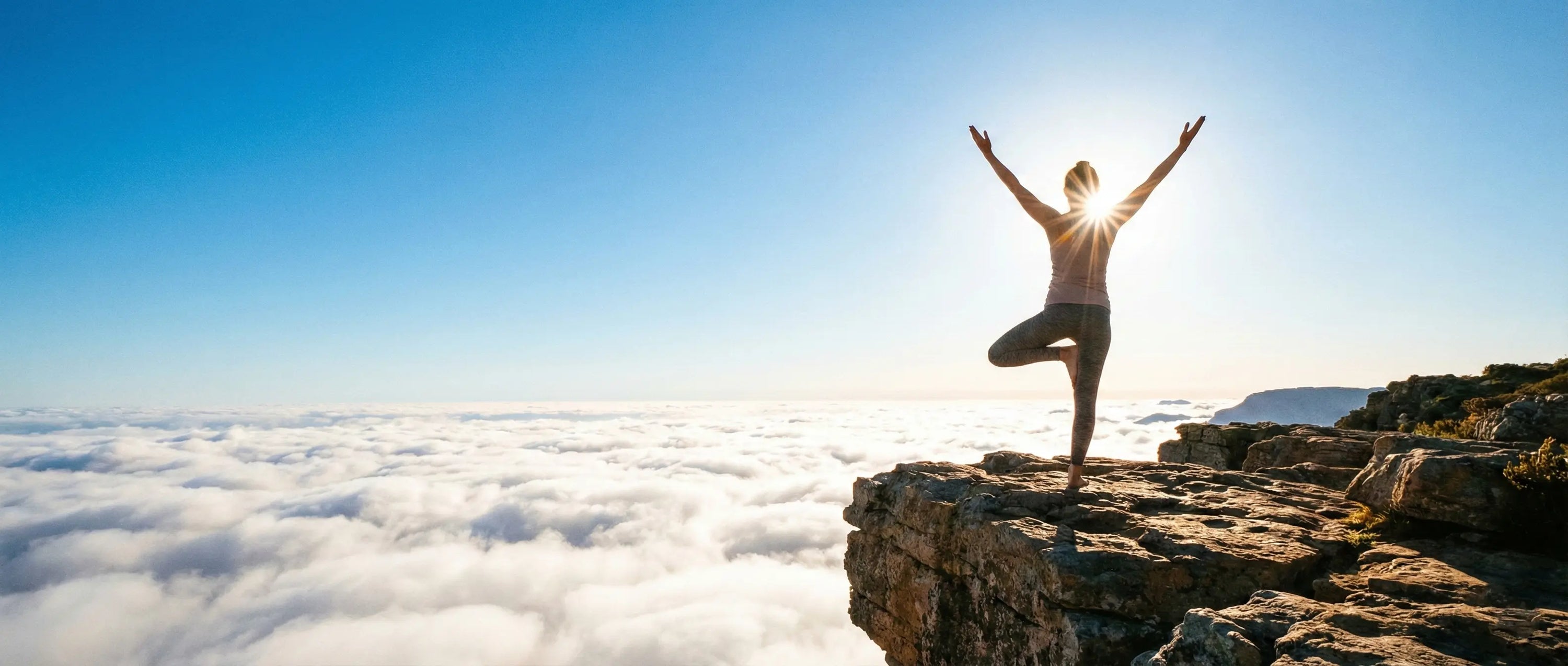 Woman practicing a gentle yoga pose on a cliff edge above the clouds, visualizing the transition from brain fog to mental clarity through breathwork and stress reduction.